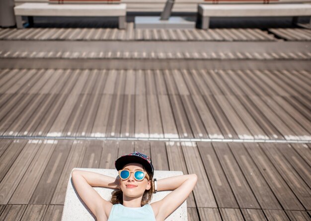 Jonge vrouw in sportkleding die rust na de training liggend op de moderne zonnebank in de stad