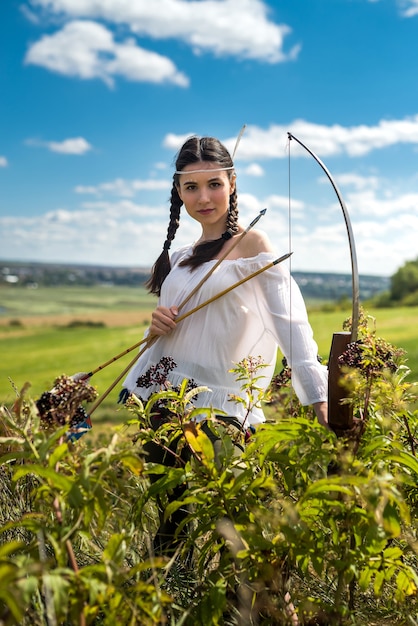 Jonge vrouw in stijl Native American Indian met pijl en boog in de natuur