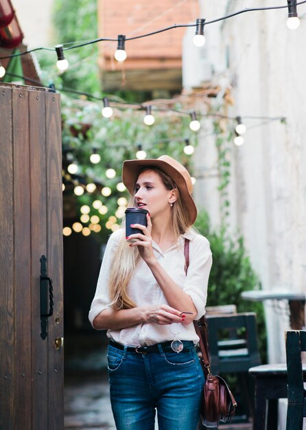 Jonge vrouw in stijlvolle kleding met een kopje koffie