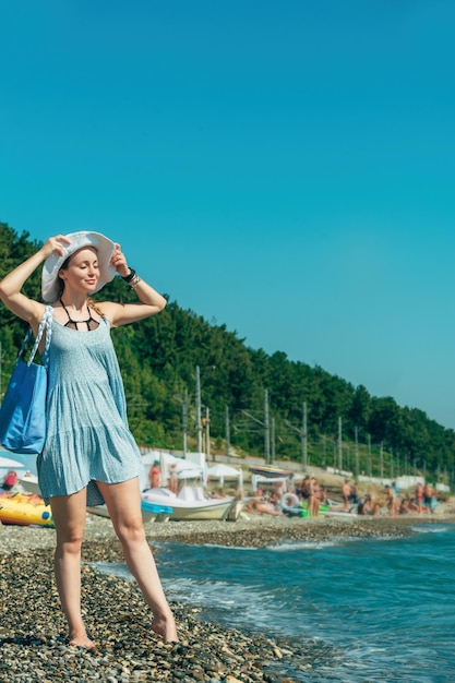 jonge vrouw in strandkleding die op een zonnige dag langs de kust loopt