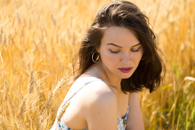 Jonge vrouw in tarweveld bij zonsondergang