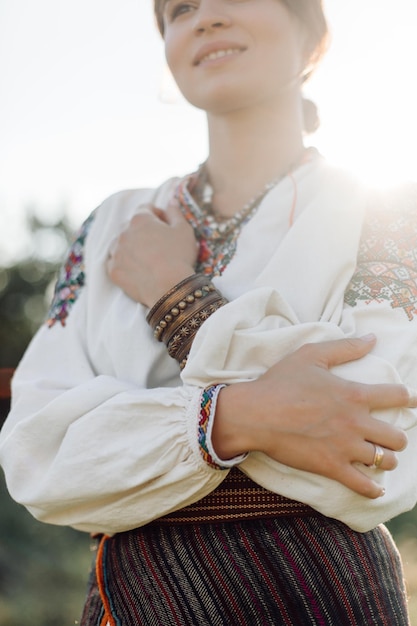 Foto jonge vrouw in traditioneel nationaal geborduurd overhemd en rok op de natuur bij zonsondergang etnische nationale kledingstijl geborduurd overhemd