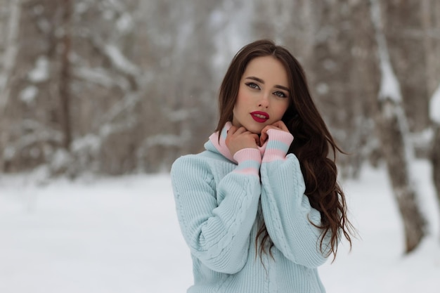 Jonge vrouw in trendy warme kleren die lacht voor de camera en lang haar aanpast