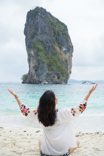 Jonge vrouw in vergadering gelukkig op zand. Reistour in Azië: Krabi, Thailand.