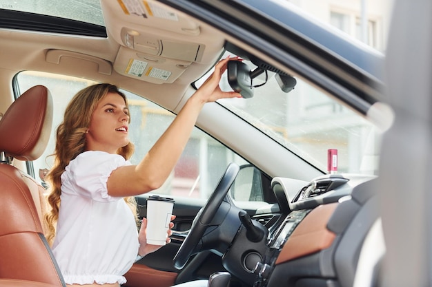 Jonge vrouw in vrijetijdskleding zit overdag in haar auto