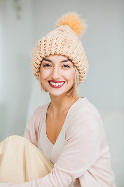 Jonge vrouw in warme beige hand gebreide muts thuis