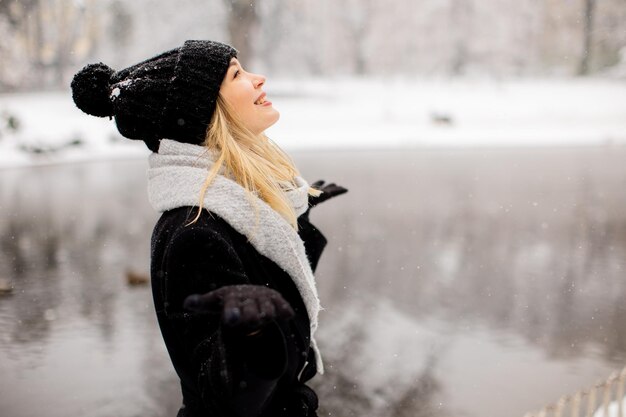 Jonge vrouw in warme kleren geniet in de sneeuw.