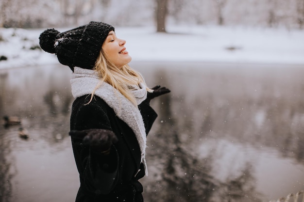Jonge vrouw in warme kleren geniet in de sneeuw.