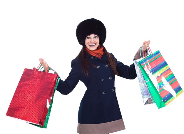 Jonge vrouw in winterkleren met boodschappentassen. geïsoleerd op een witte achtergrond