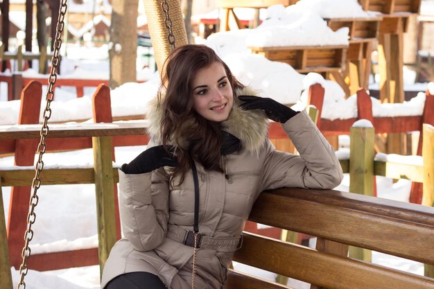 Foto jonge vrouw in winterpark zittend op een bankje met veel sneeuw eromheen