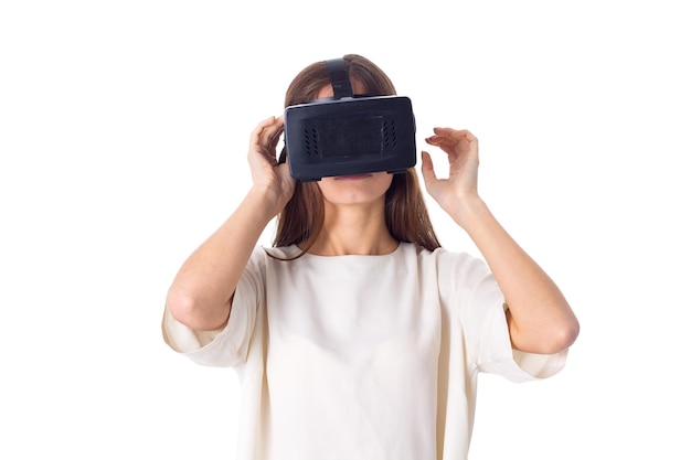 Jonge vrouw in wit overhemd met behulp van virtual reality-bril op witte achtergrond in studio