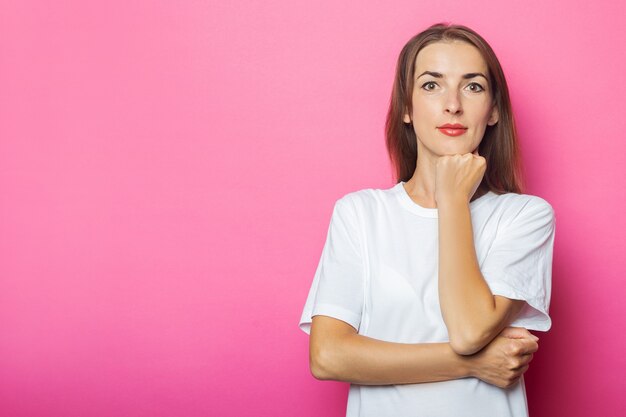 Jonge vrouw in wit t-shirt houdt hand onder de kin