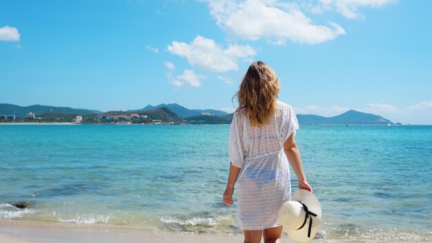 Jonge vrouw in witte kleding verfrissend op het oceaanstrand, China