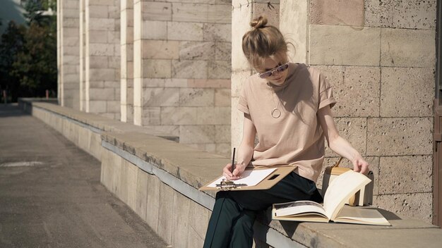 Jonge vrouw in zonnebril voorbereiden op het examen buiten