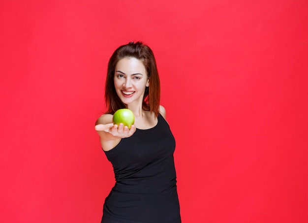 Jonge vrouw in zwart hemd die groene appels vasthoudt en ze deelt met een vriend