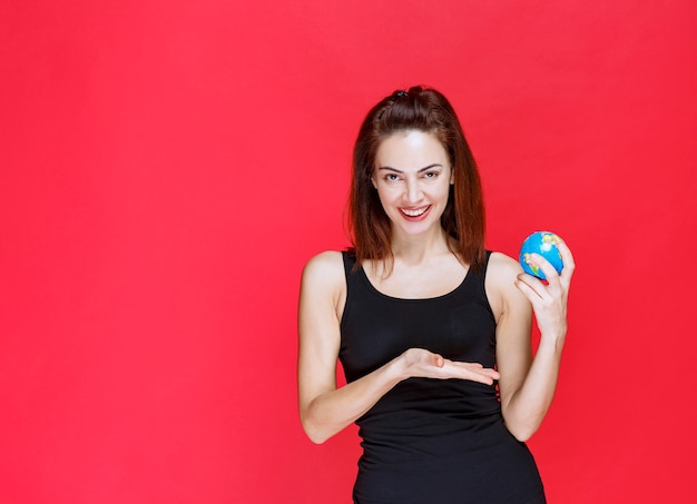 Jonge vrouw in zwart hemd met een mini-wereldbol