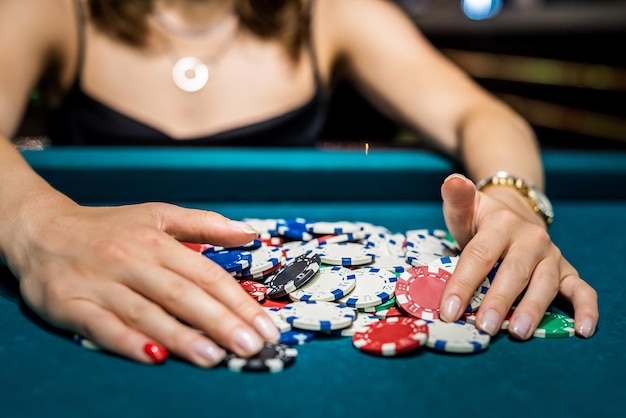 Jonge vrouw in zwarte jurk wint in Blackjack-spel en verheugt zich over alle fiches na pokerspel