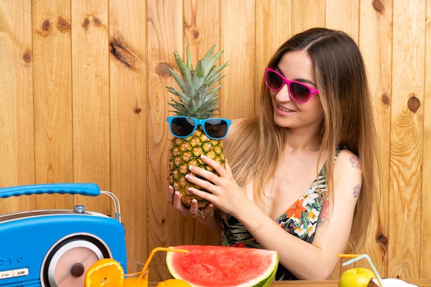 Jonge vrouw in zwempak die een ananas met zonnebril houden