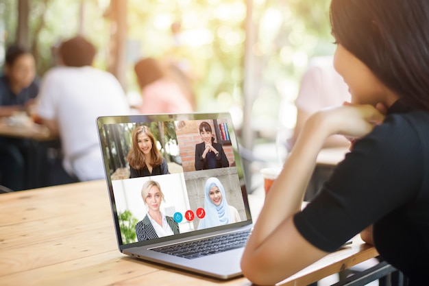 Jonge vrouw is op zoek naar haar computerscherm tijdens zakelijke bijeenkomst via video conferencing applicatie