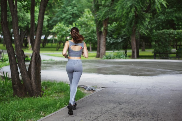 Jonge vrouw joggen langs een pad in een groen park Achteraanzicht