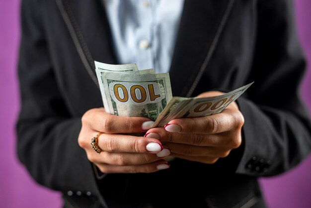 Jonge vrouw kantoormedewerker met dollars valuta rijk geïsoleerd op een achtergrond met één kleur zakelijke winst contant geld