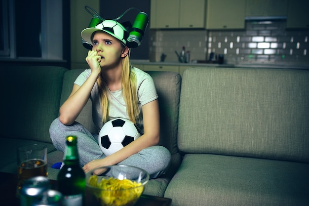 Jonge vrouw kijken voetbalwedstrijd op tv's nachts
