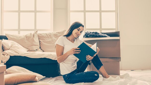 Jonge vrouw kijkt naar een tijdschrift dat in de nieuwe woonkamer ligt