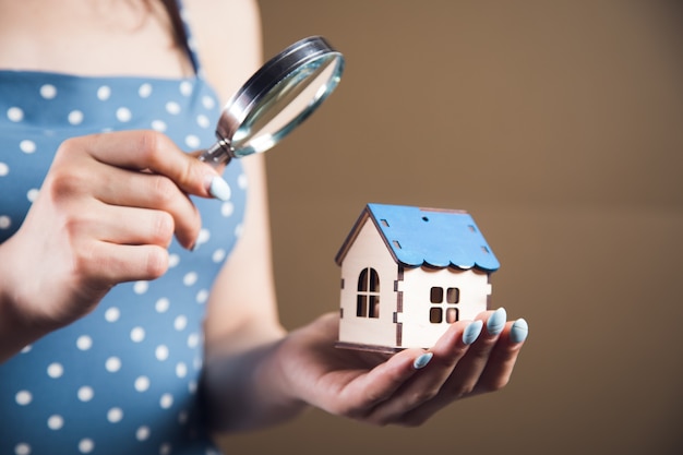 Jonge vrouw kijkt naar het huis met een vergrootglas. huiszoekconcept