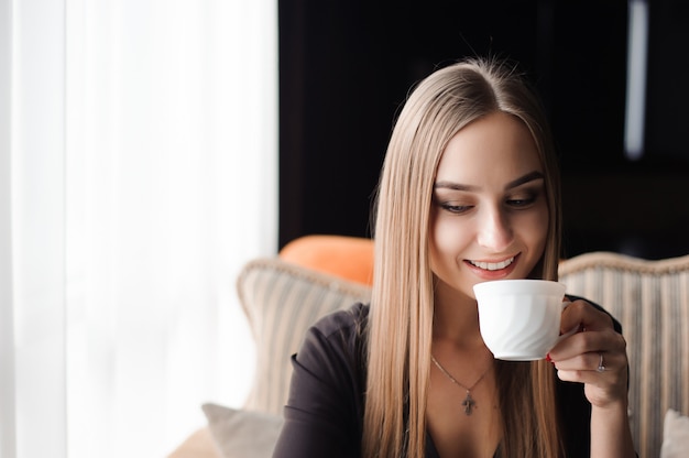 Jonge vrouw koffie drinken in een café en het gebruik van een mobiele telefoon