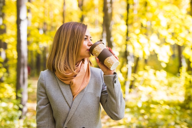 Jonge vrouw koffie drinken in herfst park