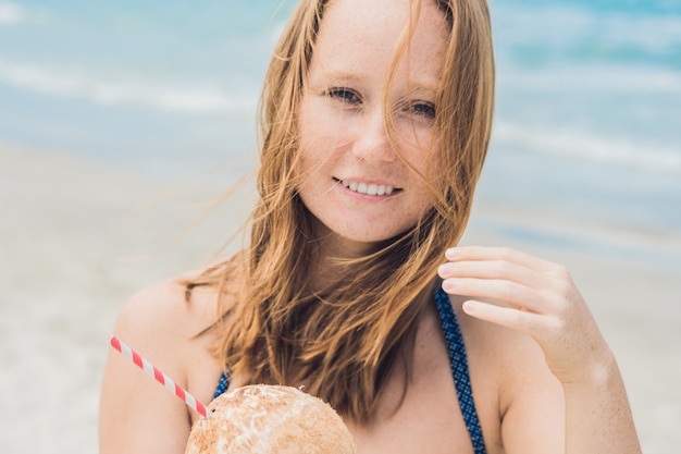 Jonge vrouw kokosmelk drinken op strand