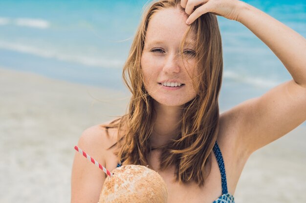 Jonge vrouw kokosmelk drinken op strand