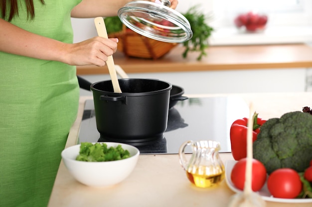 Jonge vrouw kookt bij het fornuis in de keuken, close-up.