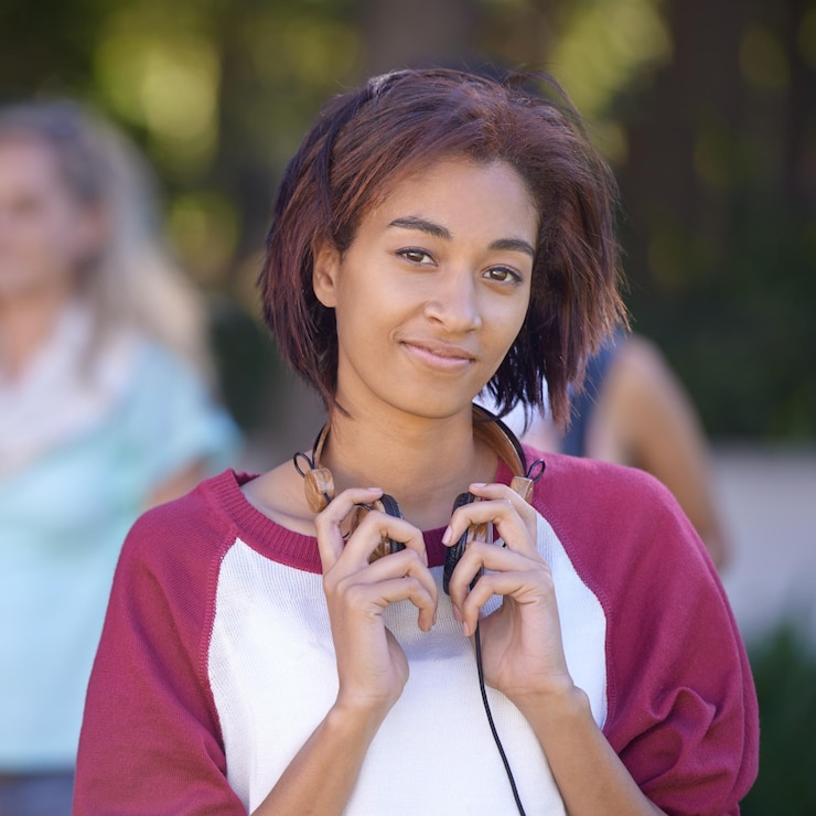 Foto jonge vrouw koptelefoon en portret op de campus gelukkig en natuur met beurs op de universiteit student glimlach en gezicht door audio elektronica muziek en universiteit buiten voor streaming podcast in het park