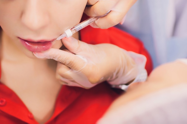 Jonge vrouw krijgt een injectie in haar lippen in schoonheidssalon. schoonheid injecties - vrouw liggend in het kantoor van de schoonheidsspecialiste. lippen verhogen door hyaluronzuur, contourprocedure, revitalisatie