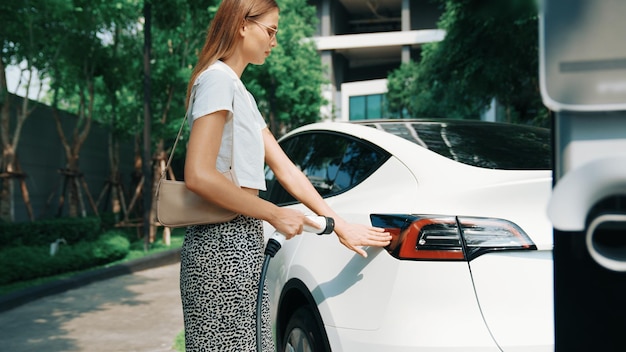 Jonge vrouw laadt accu's van elektrische auto's op in appartementen.