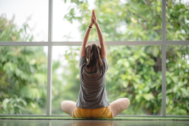 Jonge vrouw leert thuis yoga met behulp van video online training sexy schattig meisje is ontspannen met sport en externe fitness oefening levensstijl binnen thuis geïsoleerd quarantaine thuis concept