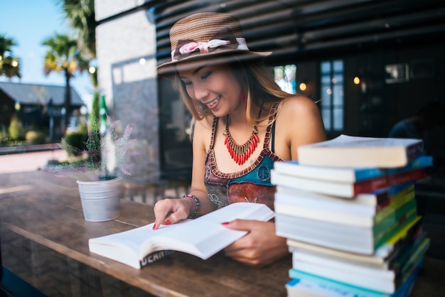 Jonge vrouw leesboek en verse kop koffie op de tafel