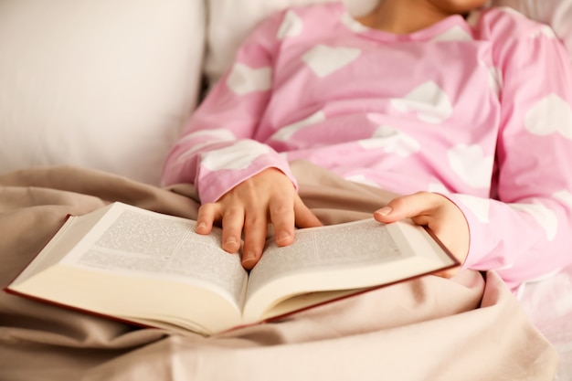 Jonge vrouw leesboek in bed thuis