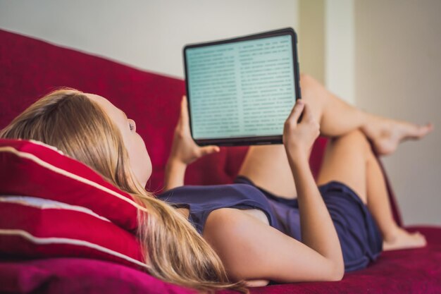 Jonge vrouw leest ebook thuis op de bank