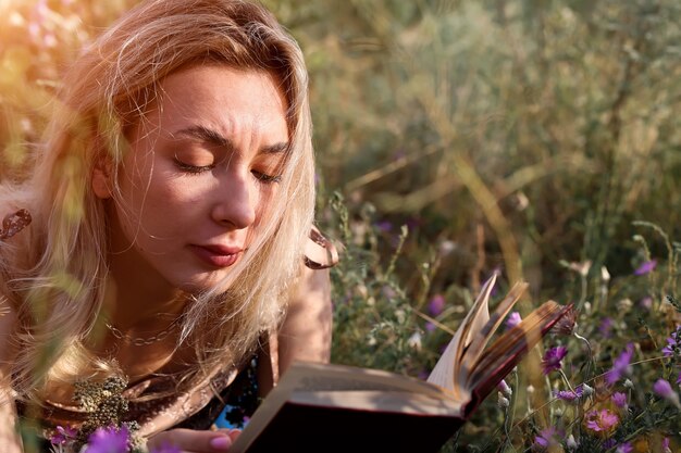 Jonge vrouw leest een boek in het veld in de natuur zomeravond