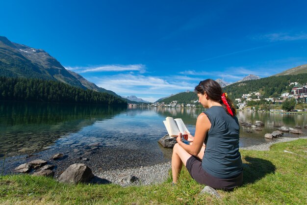 Jonge vrouw leest een boek voor een bergmeer