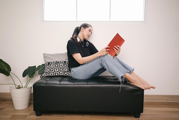 Jonge vrouw leest graag op de bank en leunt thuis op de muur ontspannen en vrijetijd in het weekend