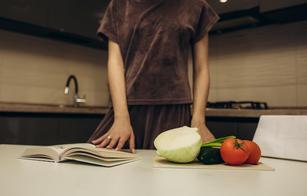 Jonge vrouw leest kookboek in de keuken op zoek naar recept