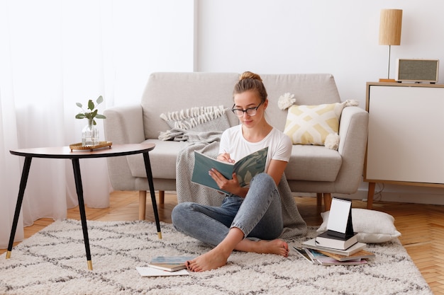 Jonge vrouw leest thuis een boek in de woonkamer