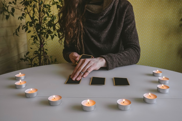 Jonge vrouw legt zwarte kaarten op de tafel met kaarslicht