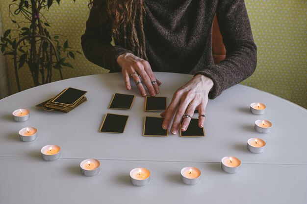 Jonge vrouw legt zwarte kaarten op de tafel met kaarslicht