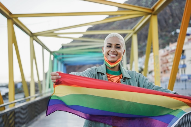 Foto jonge vrouw lgbt regenboogvlag buiten tijdens uitbraak van coronavirus - focus op gezicht