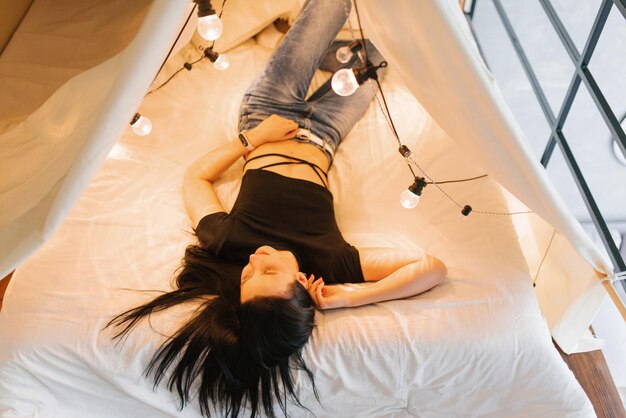 Foto jonge vrouw ligt in een bed met gloeiende gloeilampen.