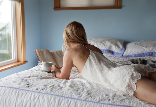 Foto jonge vrouw ligt thuis op bed.